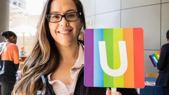 A UCLA Health staff member holding up UCLA's pride sign.