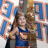 Pediatric patient Stella crashes through the banner at her superhero-reveal party