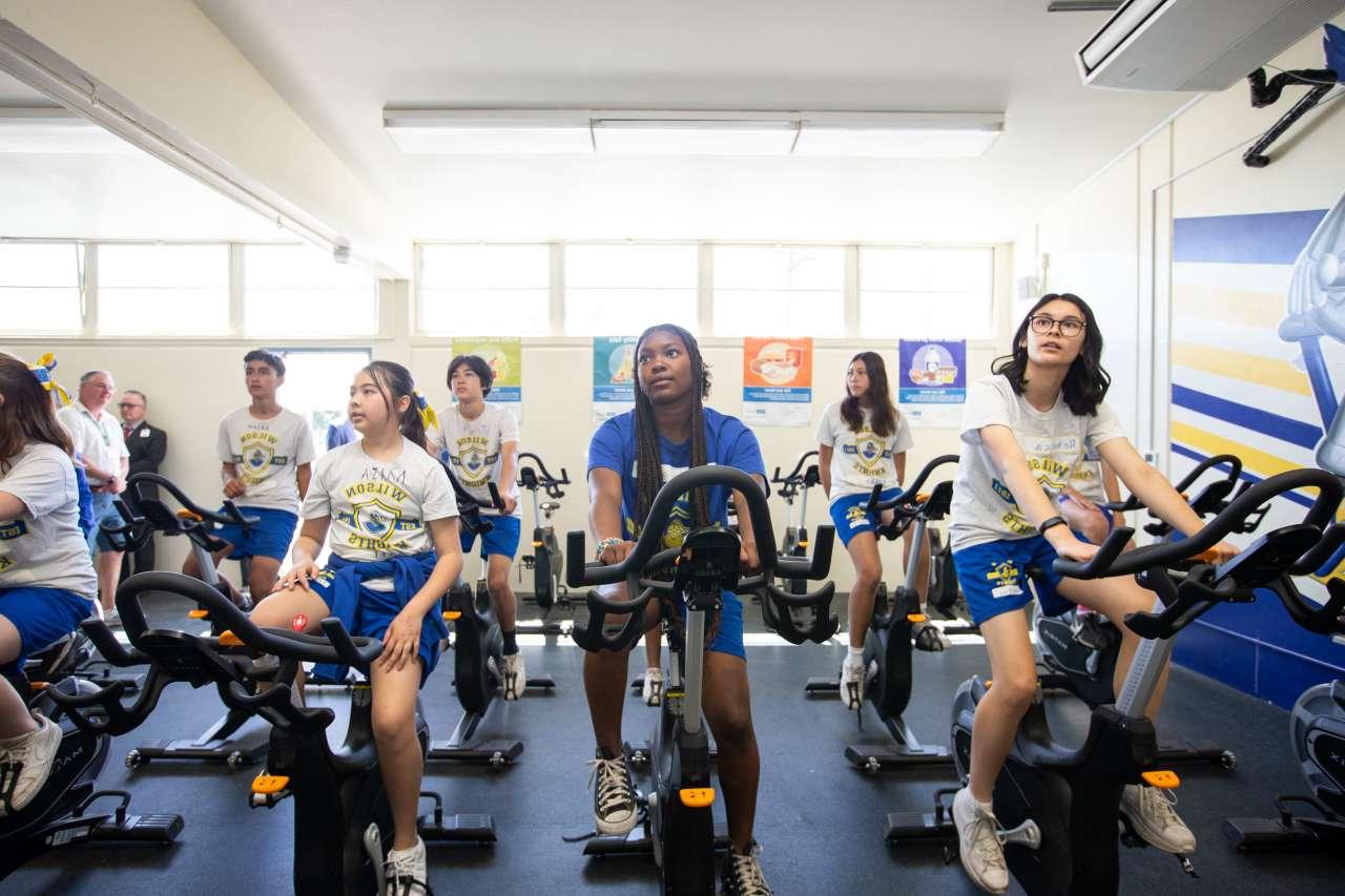 Middle school students ride exercise bikes in a new fitness room