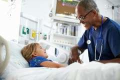 pediatrician talking to child in hospital bed